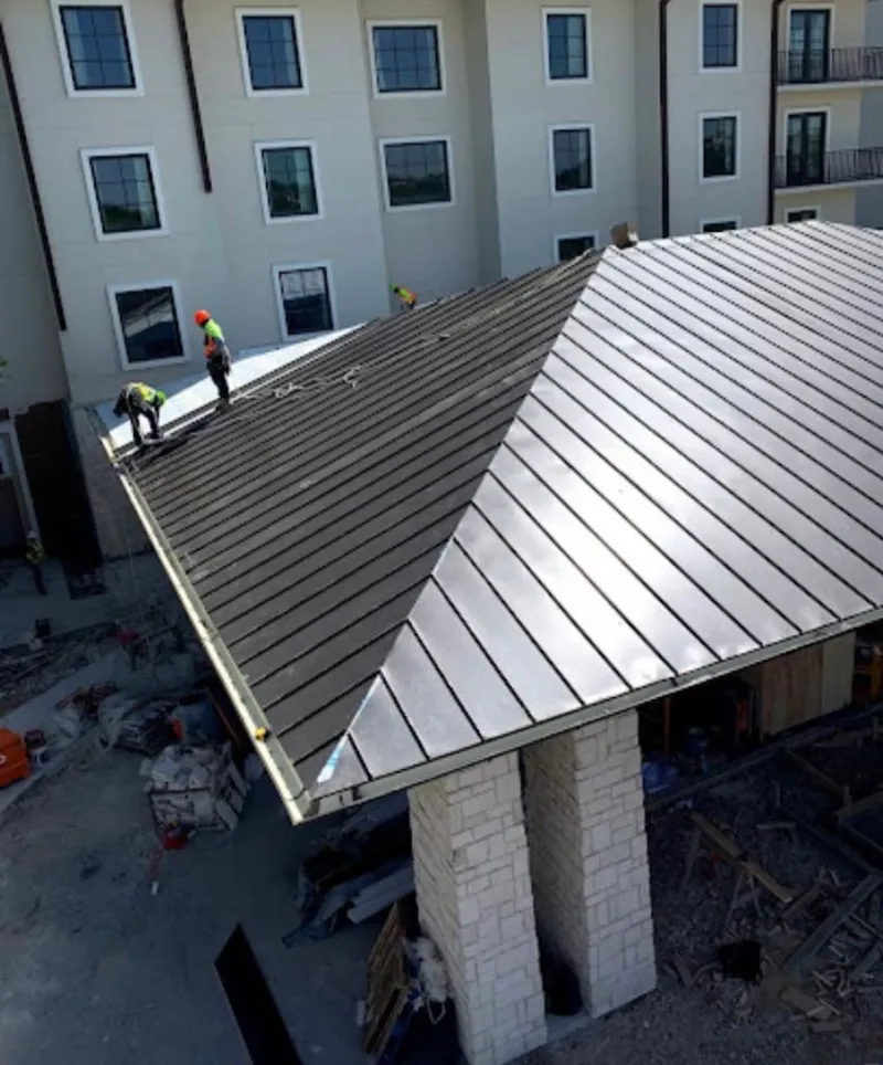 Crew installing standing seam metal roof panels on a commercial project in Summit